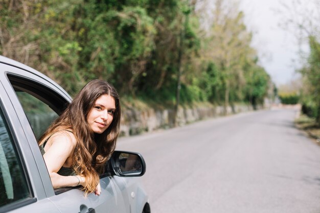 開いている車の窓の外を見ている女性