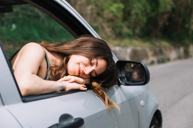 開いている車の窓の外を見ている女性