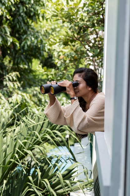 Woman looking outside with binoculars