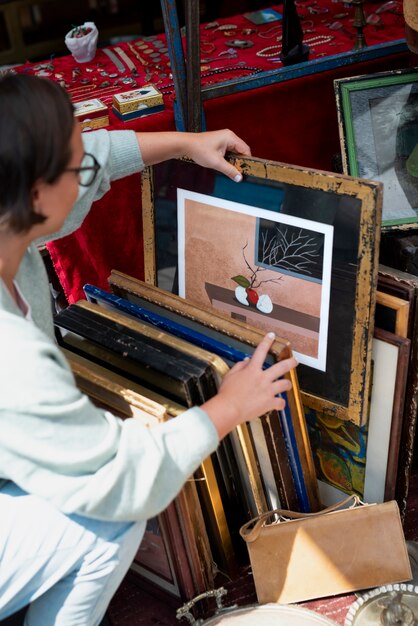 Woman looking at painting at second hand market