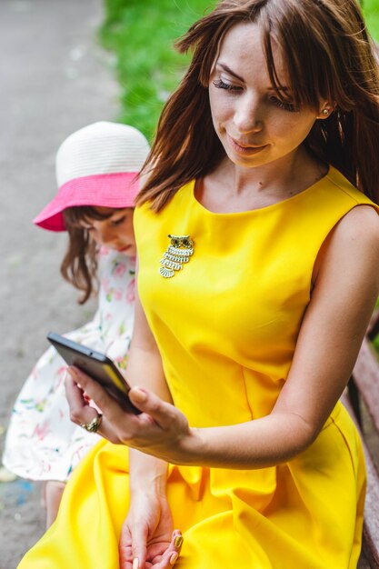 Woman looking at a phone with a little girl behind