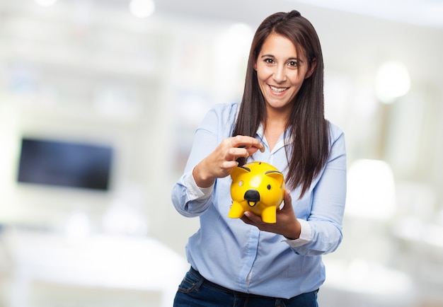 Free photo woman looking at piggy bank yellow holding in her hands