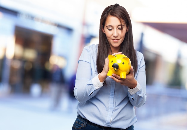 Free photo woman looking at piggy bank yellow holding in her hands