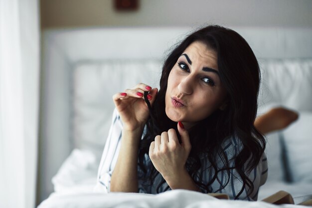 Woman looking playfully at camera on bed