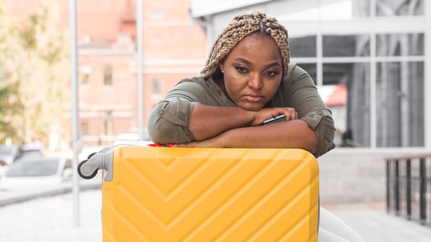 Woman looking sad while staying on her luggage