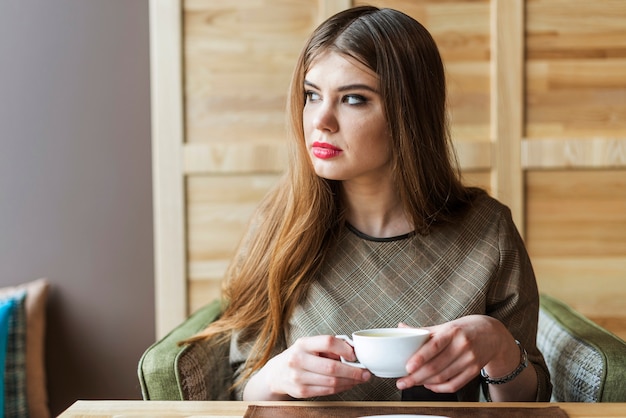 Woman looking to the side and holding a cup of tea