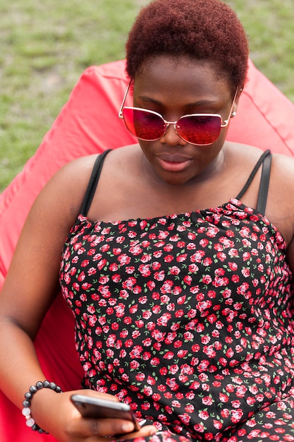 Woman looking at smartphone outdoors on bean bag