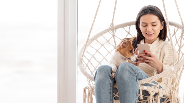 彼女の犬と一緒にスマートフォンを見ている女性