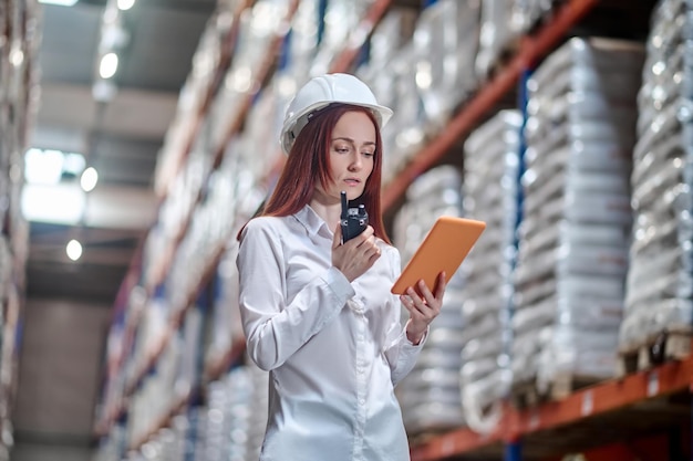 Woman looking at tablet talking on walkie-talkie