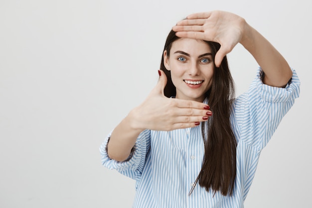 Woman looking through frame gesture, smiling as search inspiration