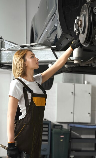 Woman looking at tire of car in auto service
