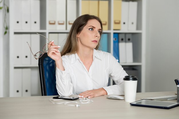 Woman looking tired at work because of her time spent on the phone