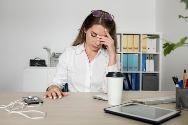 Женщина выглядит уставшей на работе из-за времени, проведенного за телефоном