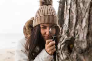 Free photo woman looking at tree bark through magnifying glass