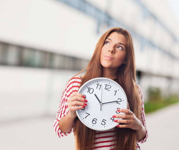 Woman looking up holding a clock