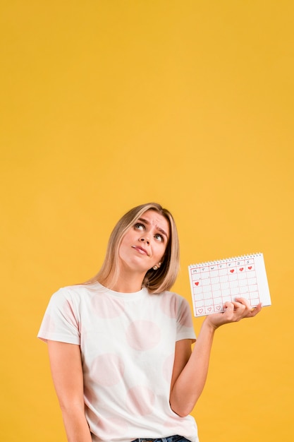 Foto gratuita donna che osserva in su e che tiene il calendario mestruale