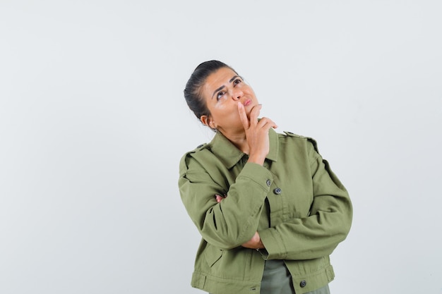 woman looking up in jacket, t-shirt and looking pensive.