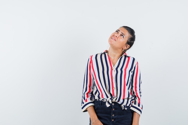 woman looking upward in shirt, skirt and looking focused