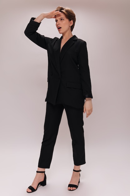 Free photo woman looks forward. portrait of lady in black outfit on white background. short-haired girl in dark suit poses on isolated