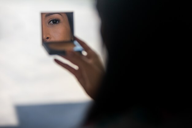 Женщина смотрит в зеркало своего порошка