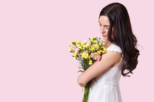 Woman looks at spring flowers, stands sideways
