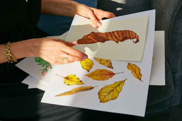 Woman looks through acrylic illustrations with autumn leaves