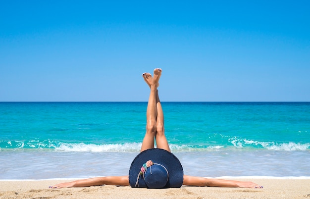 Woman lying on the beach with legs up in the air