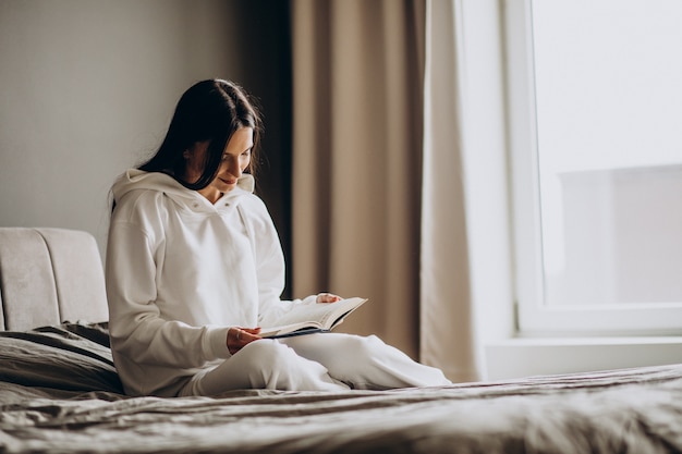 Free photo woman lying on bed and reading book