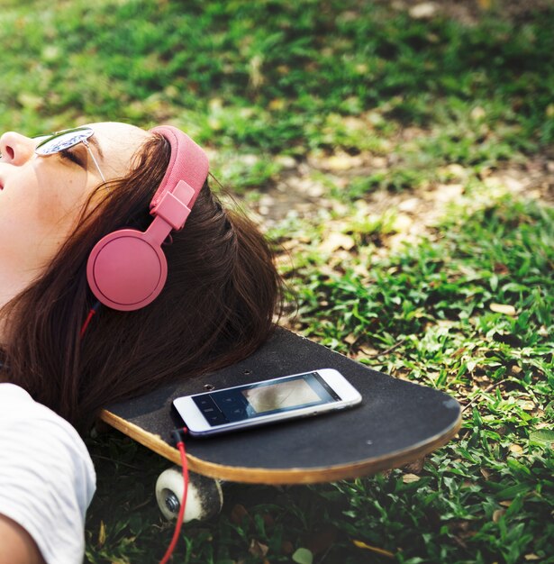 音楽を聴く草の上に横たわっている女性