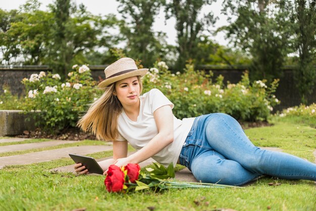 Woman lying on grass with tablet 