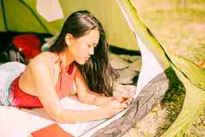 無料写真 携帯電話とテントの中で横になっている女性
