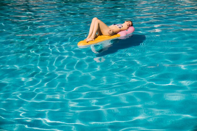 Woman lying on inflatable mattress in pool