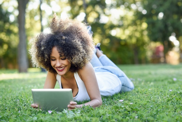 Woman lying on the lawn of a park with a laptop