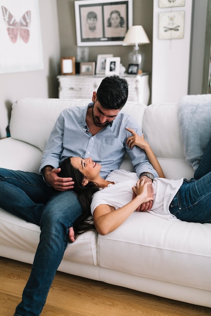 Woman lying on man's lap sitting on sofa at home