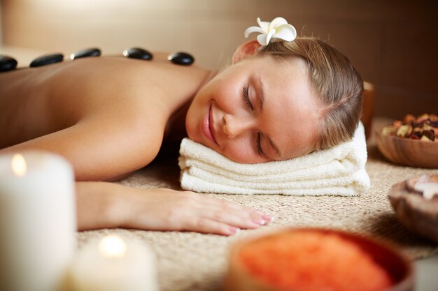 Woman lying on massage table with hot stones on her back