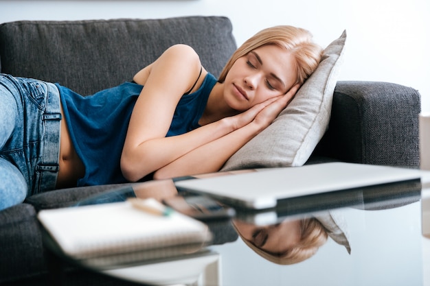 Woman lying and sleeping on couch at home