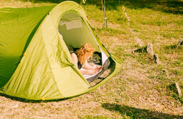 Woman lying in tent with tablet