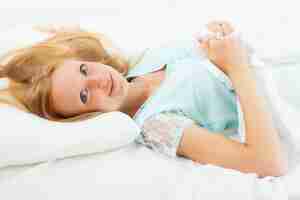 Free photo woman lying on white sheet in bed at home