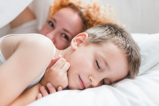 Woman lying with her sleeping son on bed
