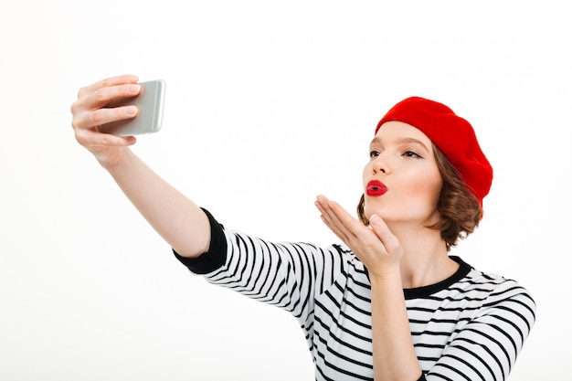 Woman make selfie by mobile phone blowing kisses.