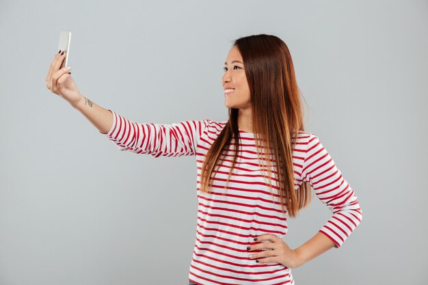 Woman make selfie by phone standing isolated