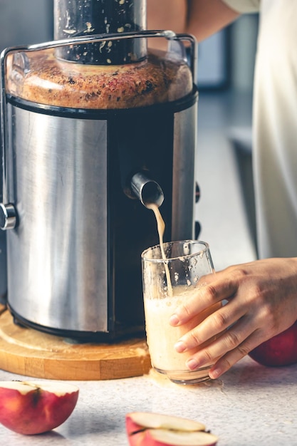 Foto gratuita una donna prepara il succo di mela a casa con uno spremiagrumi