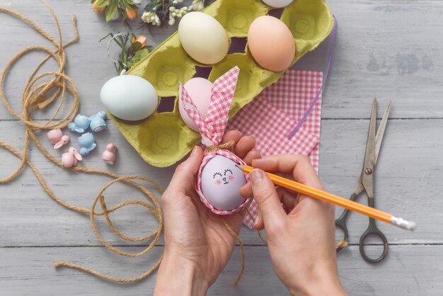 여자는 부활절 휴가를 위해 귀여운 장식 달걀을 만듭니다. diy 부활절 선물 개념입니다. 파스텔톤의 귀여운 계란