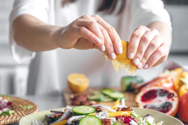 女性は、新鮮な野菜のサラダのクローズ アップを作る