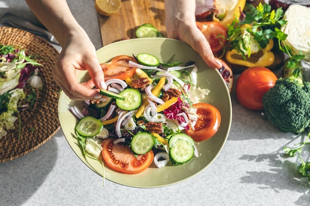 A woman makes a fresh vegetable salad closeup