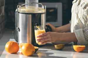 Foto gratuita una donna fa succo d'arancia a casa in cucina con un succhiatore elettrico