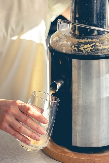 Una donna fa succo d'arancia a casa in cucina con un succhiatore elettrico