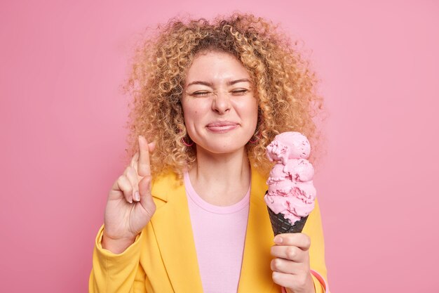 woman makes wish crosses fingers believes in good luck eats delicious cone ice cream wears yellow jacket 