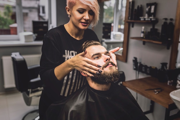 Женщина делает лечение бороды для клиента