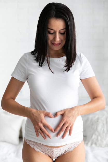 Woman making a heart on her belly